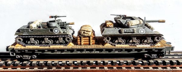 US Army M10 Tank Destroyer w/Cullen Hedgerow Device & M7 “Priest” & Supply Load on 50′ Flat Car USAX 23530(MV11C+13-FC6.2USA)_Operates on 3-Rail “O”Gauge track  • Available Today • (CTN 24)